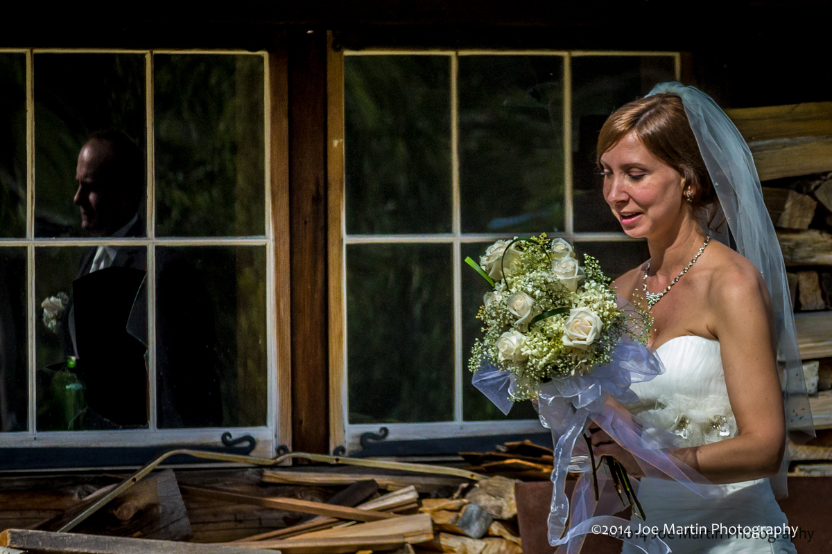 A bride walking after formal portraits with a reflection of the groom in the widows.